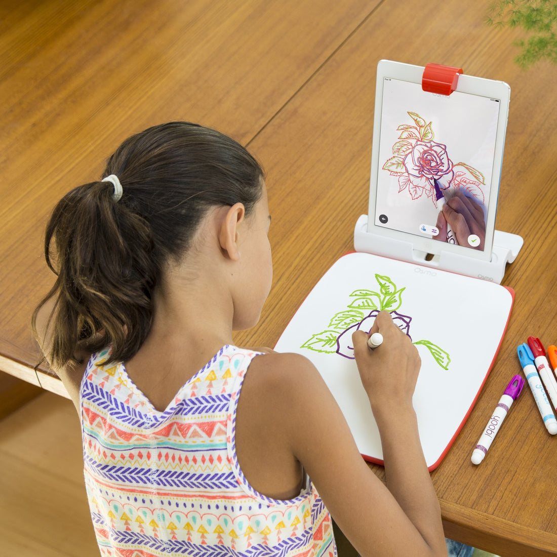 A girl copying a rose onto the Creative Board while the iPad shows the step-by-step guide in Osmo Masterpiece