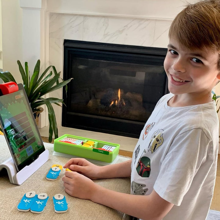 A boy playing Osmo Coding Starter Kit with coding blocks at home
