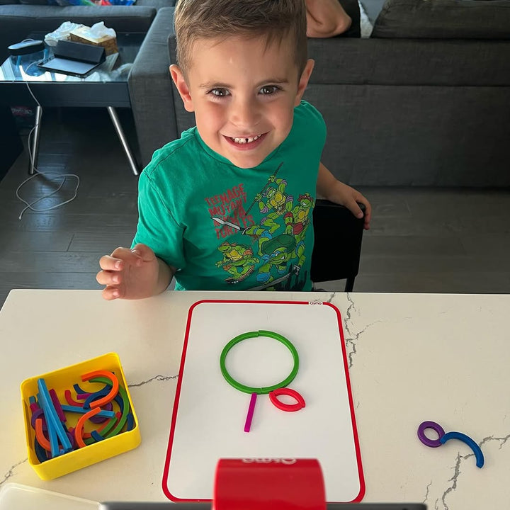 A smiling boy with a letter he built from Sticks and Rings