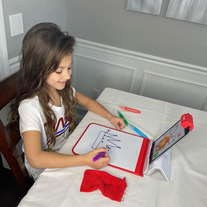 A smiling girl drawing on the Creative Board at the kitchen table