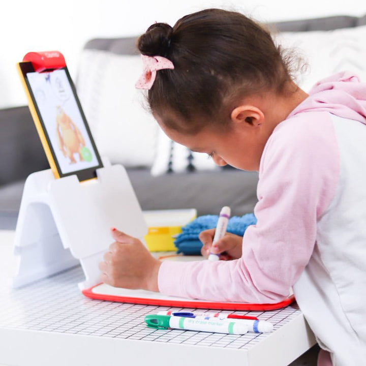 A girl in a pink hoodie drawing on the Creative Board with the tablet in front of her