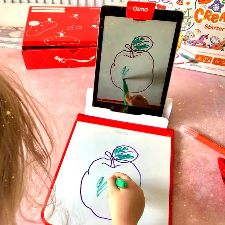 A child colouring in an apple on the Creative Board while the same drawing appears on the tablet