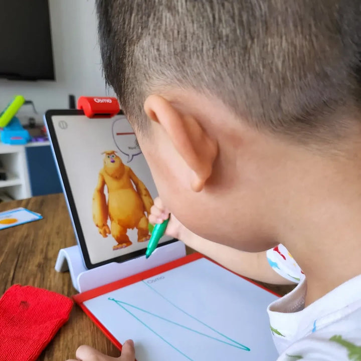 A boy drawing a line on the Creative Board while Mo the monster watches from the tablet