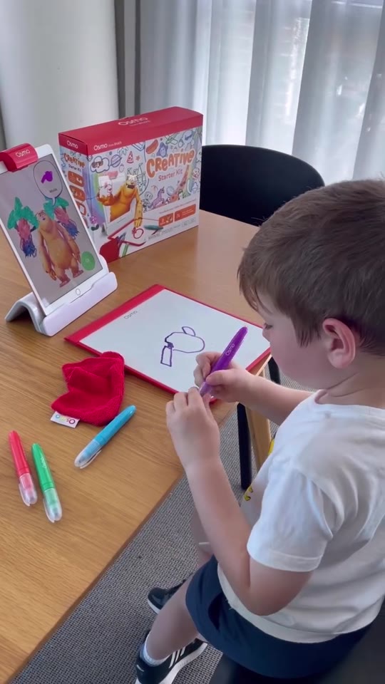 A boy drawing a watering can on the Creative Board next to the Creative Starter Kit box
