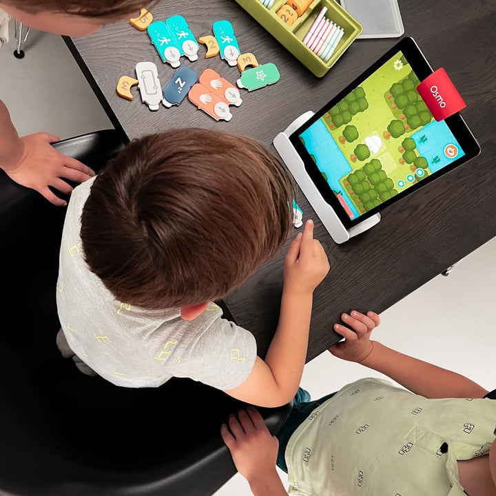 Kids around a dark table with Coding blocks and the Coding Starter Kit box open next to the iPad