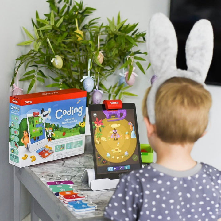 A boy in bunny ears and a toddler with the Coding Starter Kit box, tablet and blocks on a side table