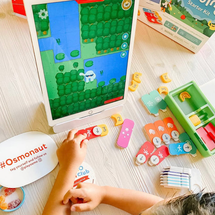 A big tablet with the Coding game and a child arranging colorful coding blocks on the table