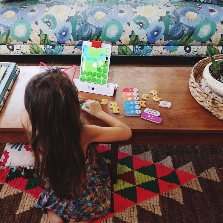 A girl on the floor placing Coding blocks in front of the iPad on a coffee table