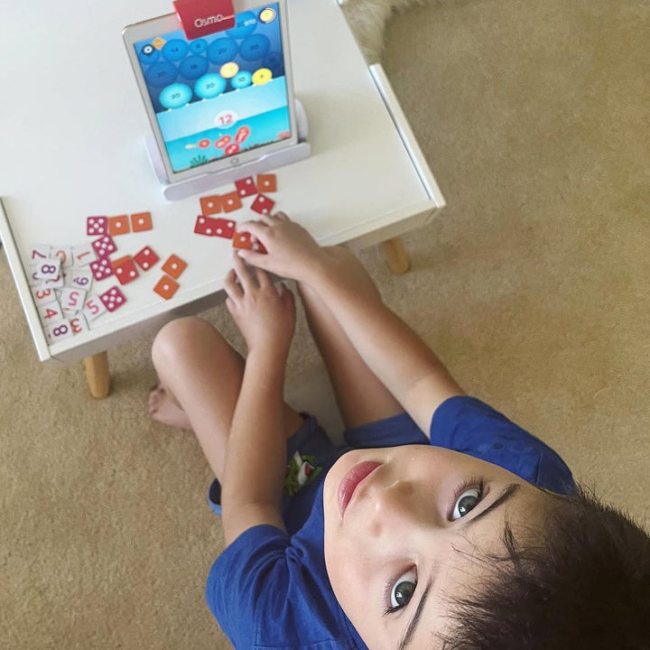A boy playing Osmo Numbers on the floor