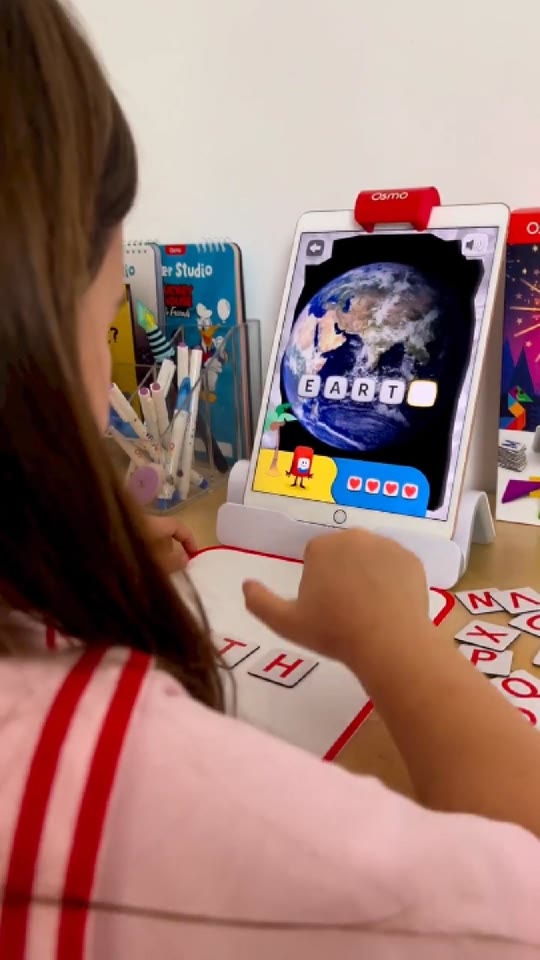 A girl spelling EARTH with Osmo Words letter tiles