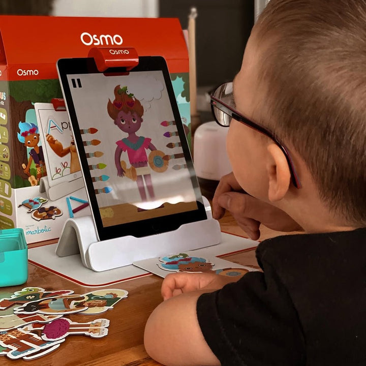 A boy playing Costume Party in front of the Little Genius Starter Kit box