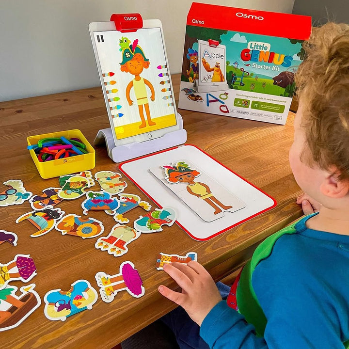 A boy playing Costume Party next to the Little Genius Starter Kit box
