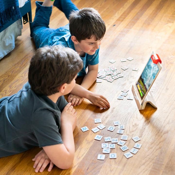 Two boys lying on the floor playing Osmo Words with letter tiles